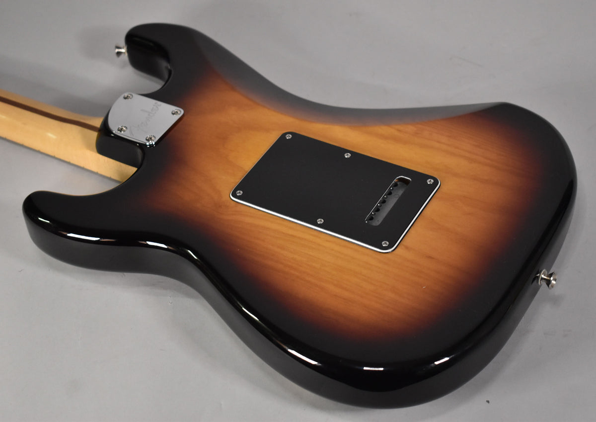 The back of a glossy 3-tone sunburst Stratocaster, showing the black tremolo cover and chrome neck plate.