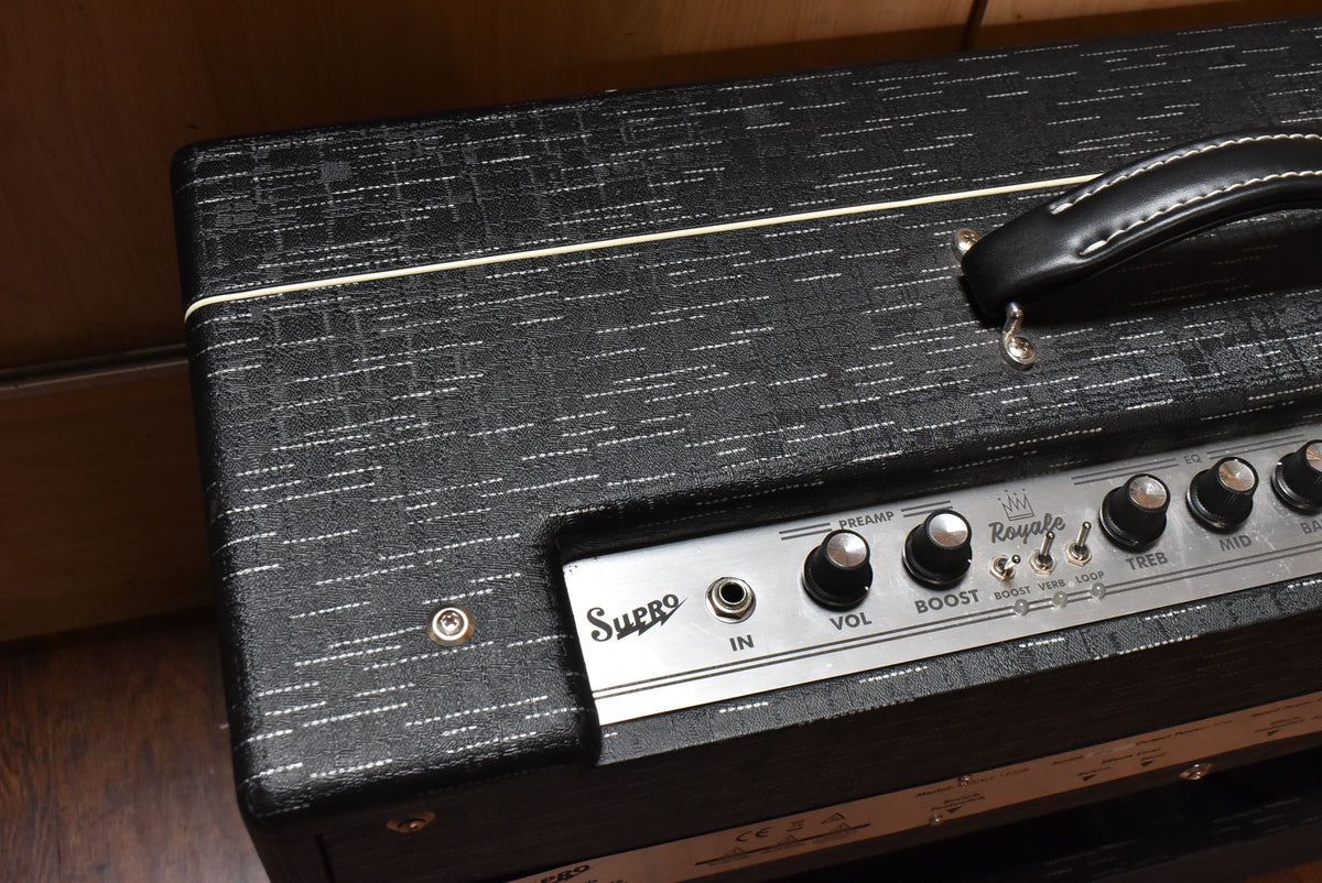 Top-down view of the black textured amp with a white stripe, showing the silver control panel with black knobs and a leather handle.