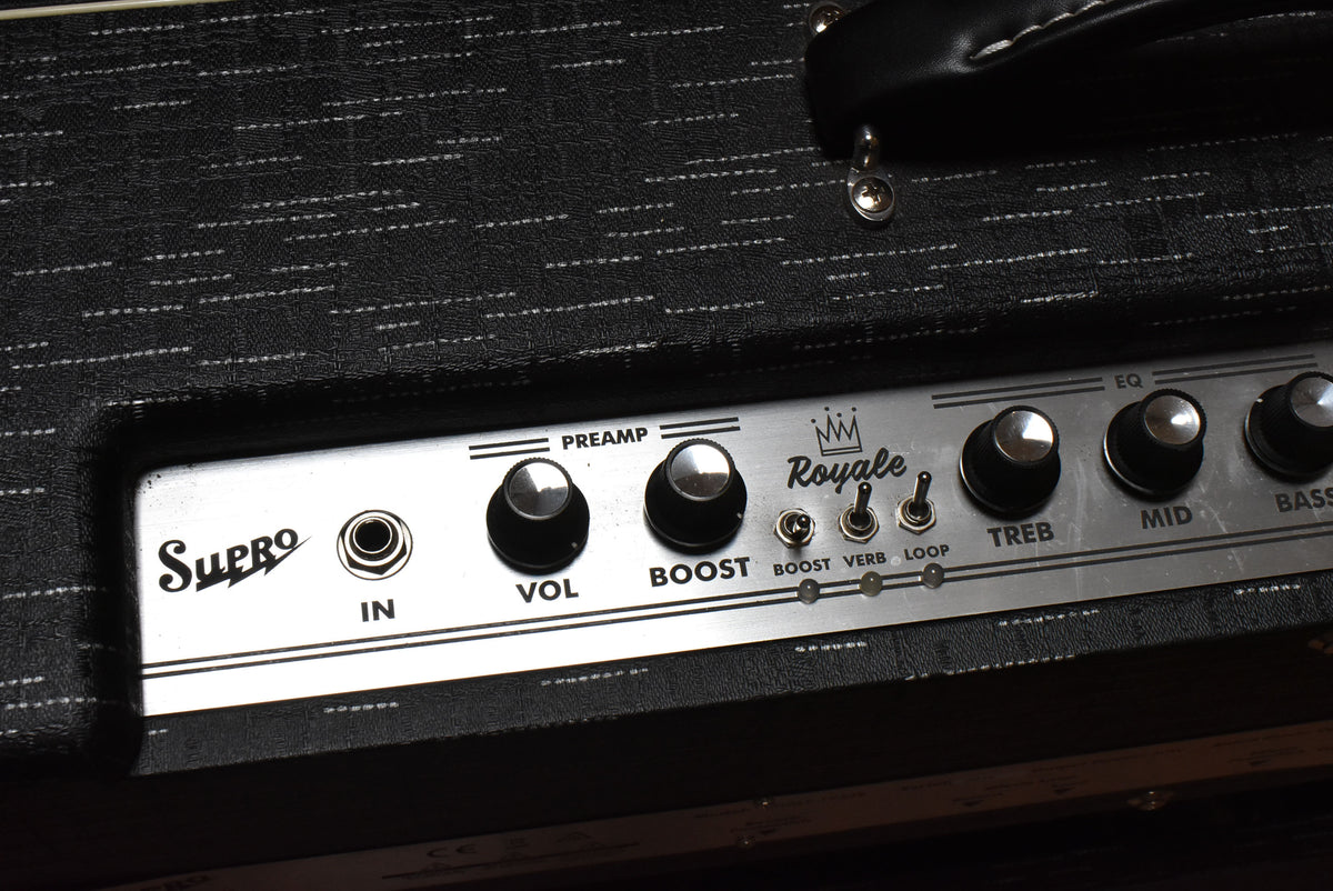Close-up of the amp's black textured top, showing the silver control panel with black knobs, three toggle switches, and a handle.
