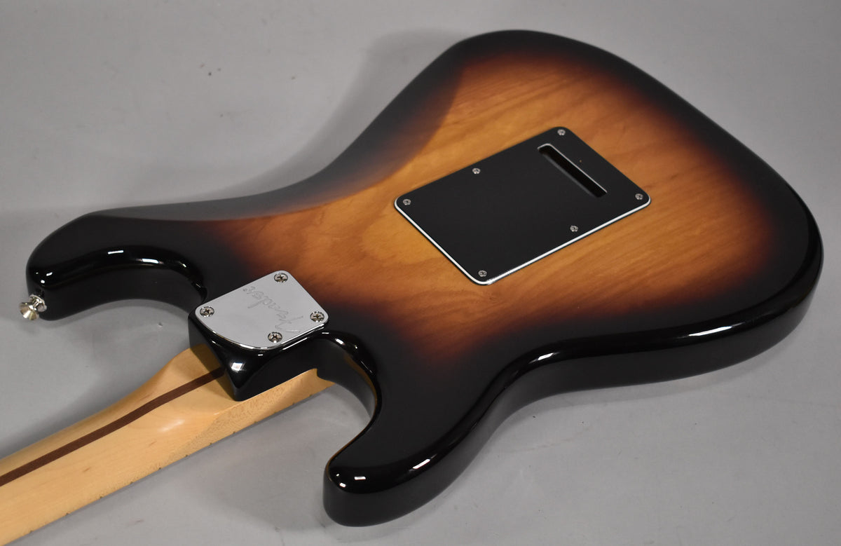 The guitar's glossy 3-tone sunburst back, showing the black tremolo cavity cover and chrome neck plate, with a light maple neck.