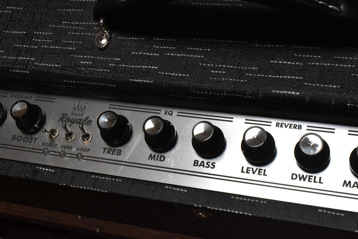 Close-up of the amp's silver control panel with black knobs and three toggle switches, showing some light scratches on the surface.