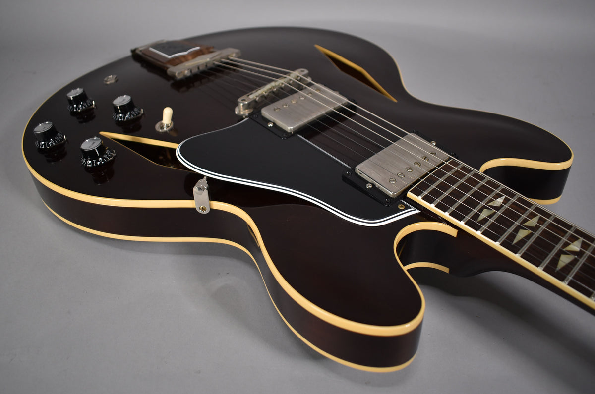 Upper body of a dark walnut semi-hollow guitar with cream binding, black pickguard, two humbuckers, and four black control knobs.