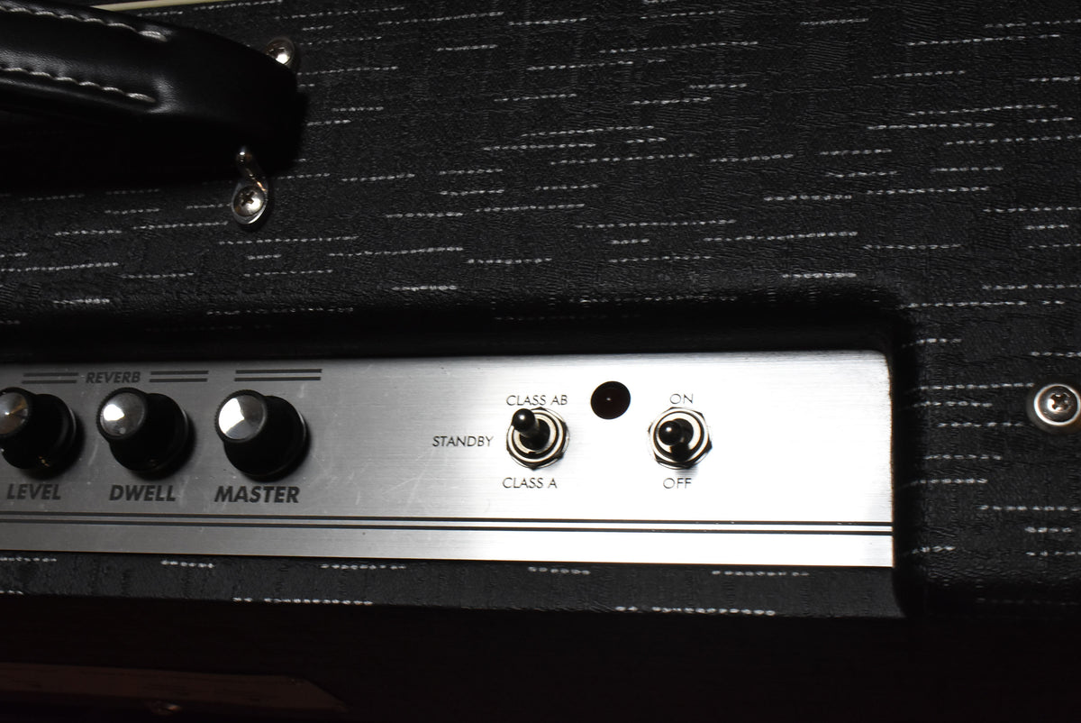 Close-up of the amp's black textured top, showing the silver control panel with three reverb knobs, a standby switch, and an on/off switch.