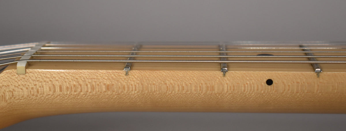 Close-up of the light-colored maple neck and fretboard, showing the nut, frets, strings, and a black dot inlay.