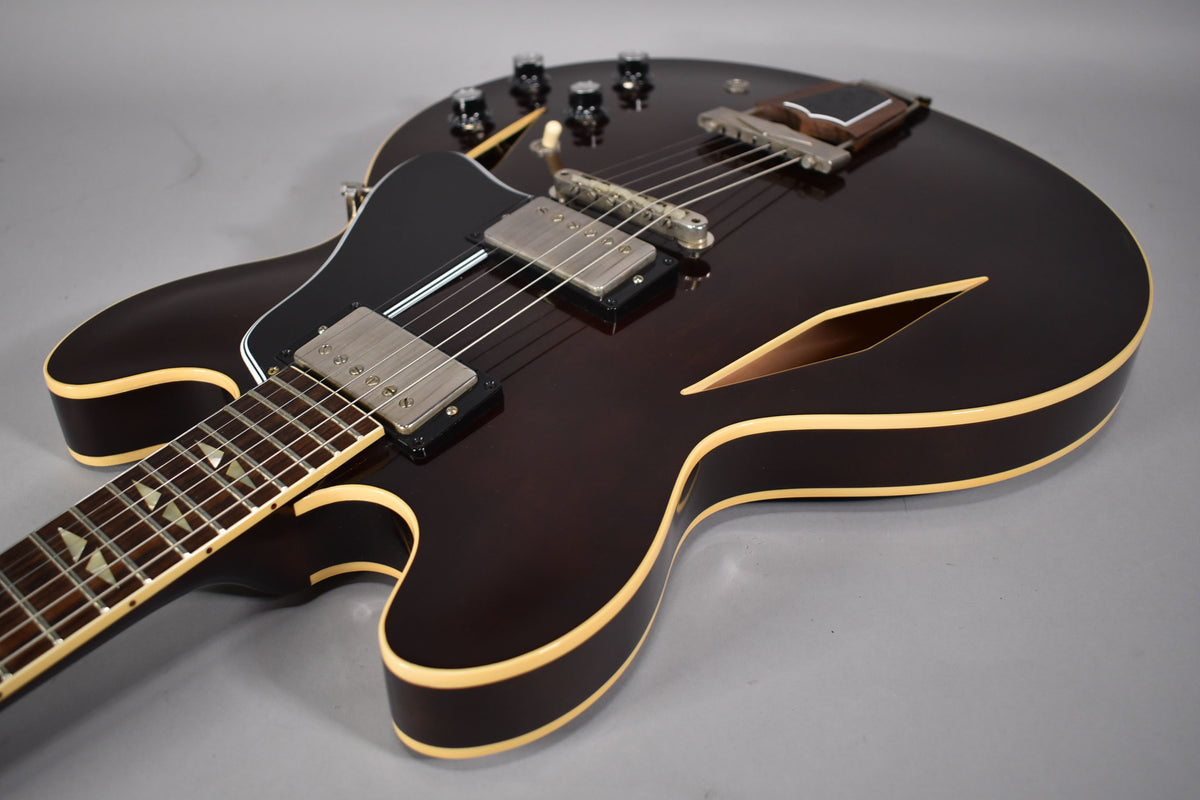 Dark walnut semi-hollowbody electric guitar with cream binding, black pickguard, two humbuckers, and trapezoid fretboard inlays.