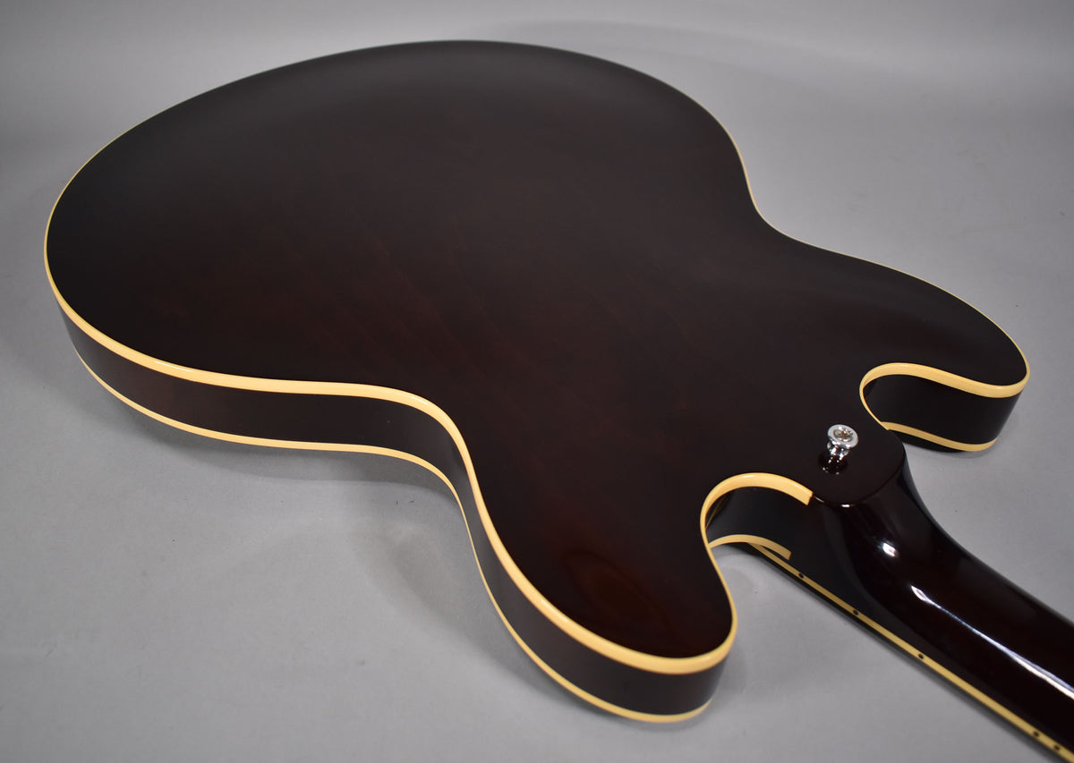 The guitar's dark walnut back and neck are visible from the upper bout, with cream binding along the body and neck heel.
