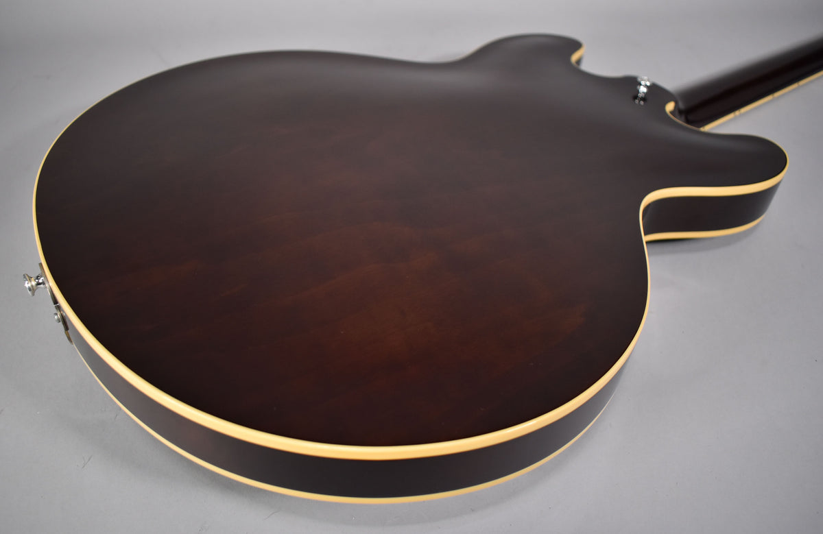 The back of a dark walnut semi-hollow electric guitar, showing the body's binding and the neck heel from an upper-right angle.