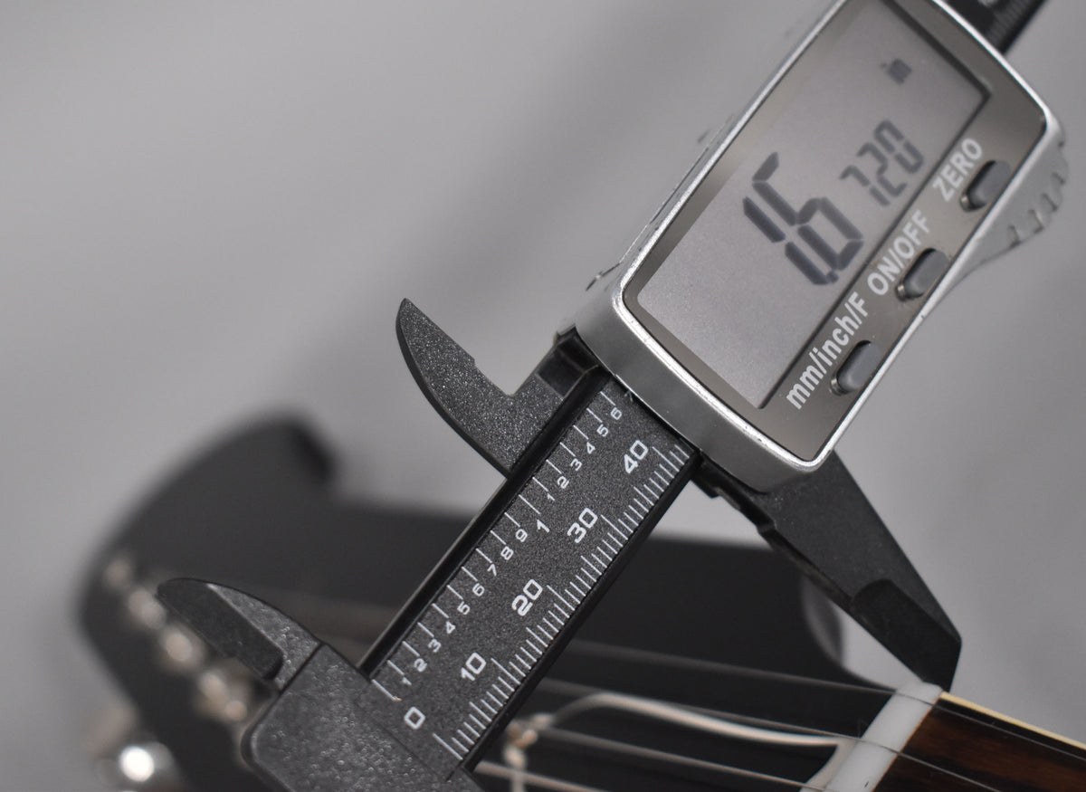 A digital caliper measures the guitar's nut width at 1.720 inches, with the fretboard and strings visible below.