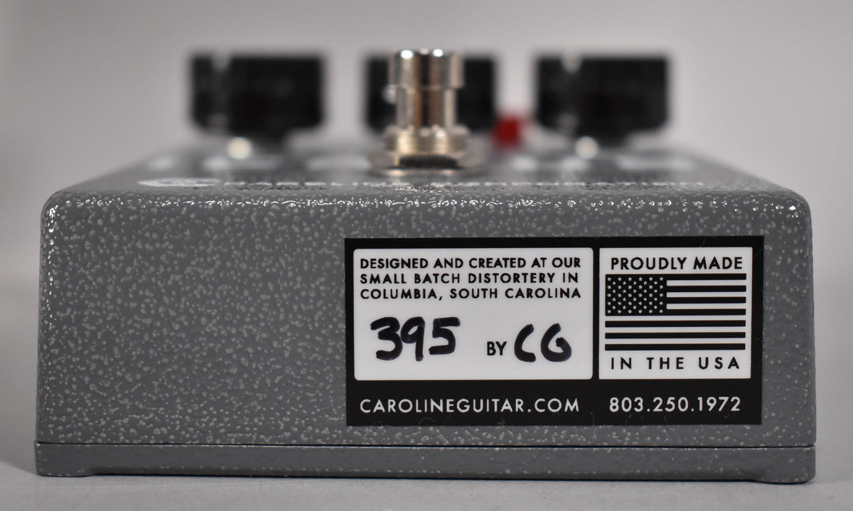 The gray, speckled effect pedal is viewed from the back, showing a white label with black text and an American flag.