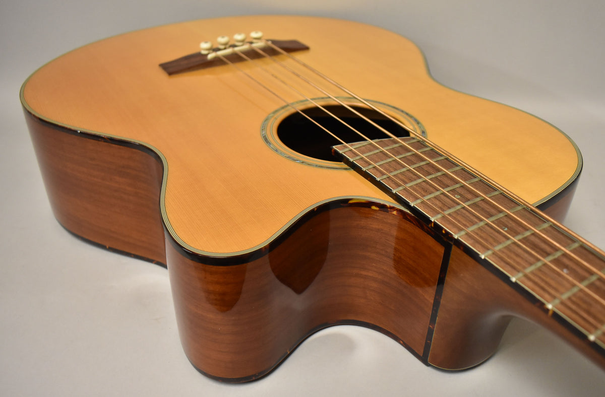 The natural acoustic bass is angled from the upper left, showing its light top, dark sides, cutaway, and fretboard.