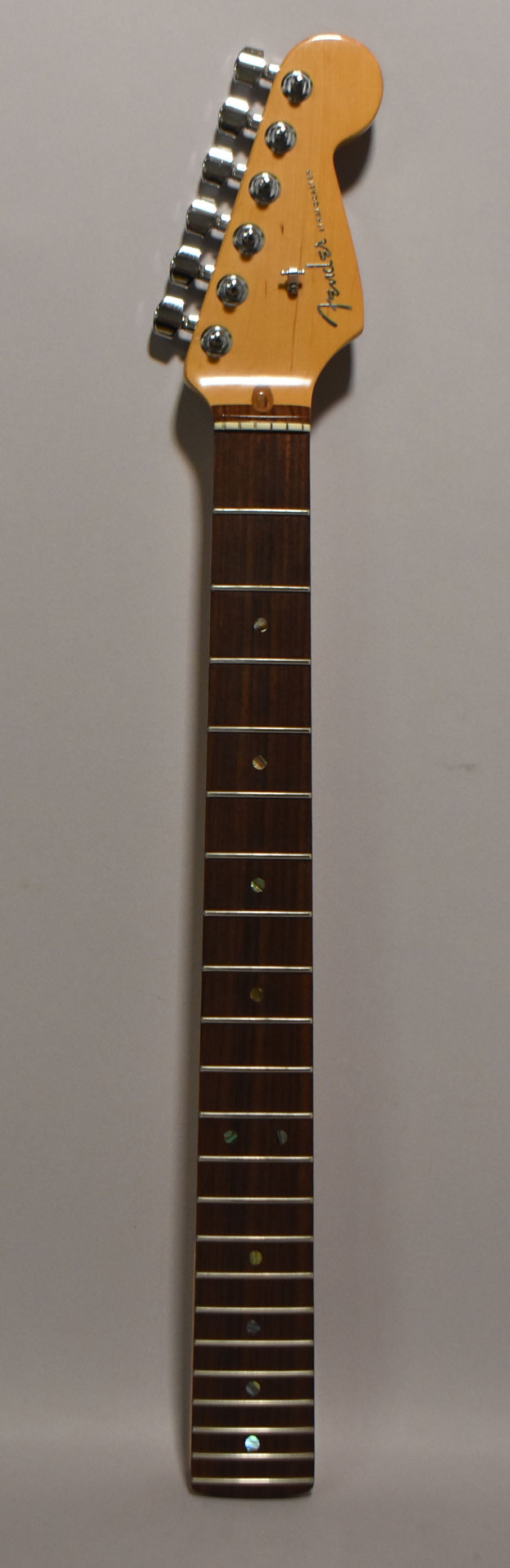 A full-length view of a light-colored maple neck with a dark rosewood fretboard, chrome tuners, and iridescent dot inlays.