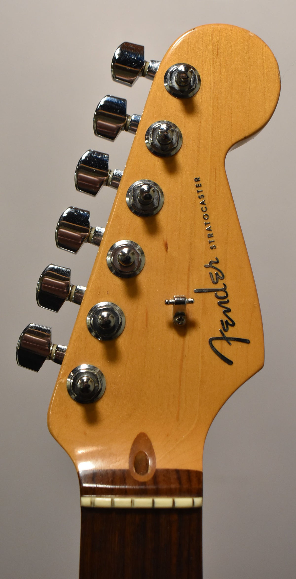 Close-up of a light maple headstock with six chrome tuners and a string tree, showing a dark rosewood fretboard.