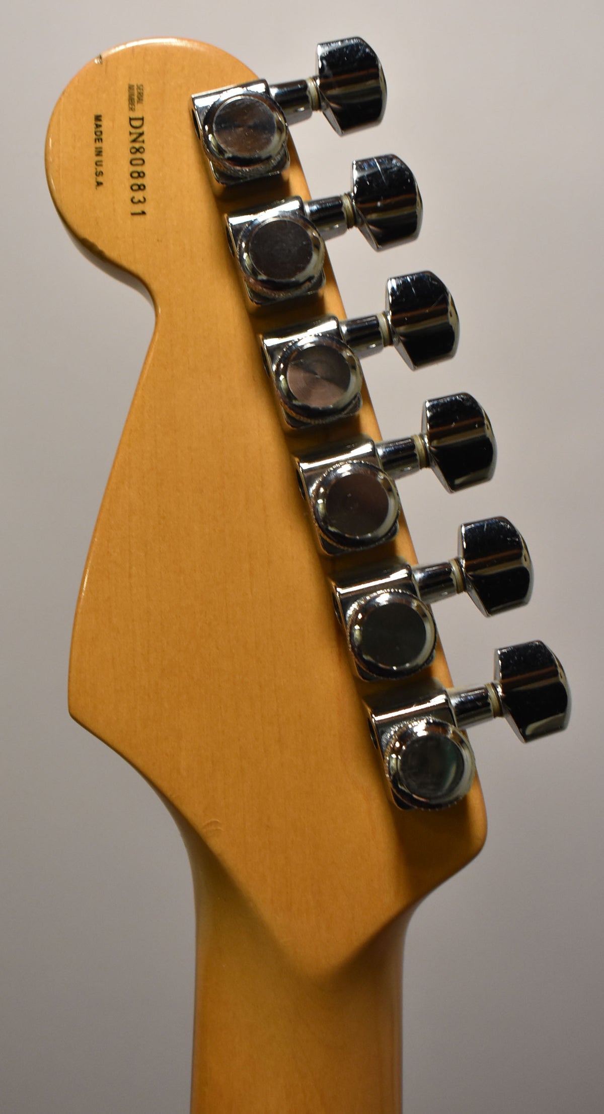 The maple headstock, with a light amber finish, shows six chrome tuners and some minor wear on the top edge.