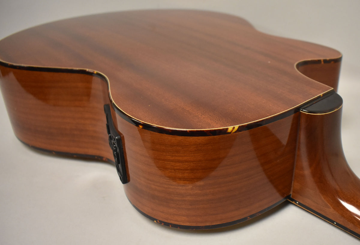 The acoustic bass's glossy natural finish body and cutaway show tortoise shell binding and a black preamp control panel.