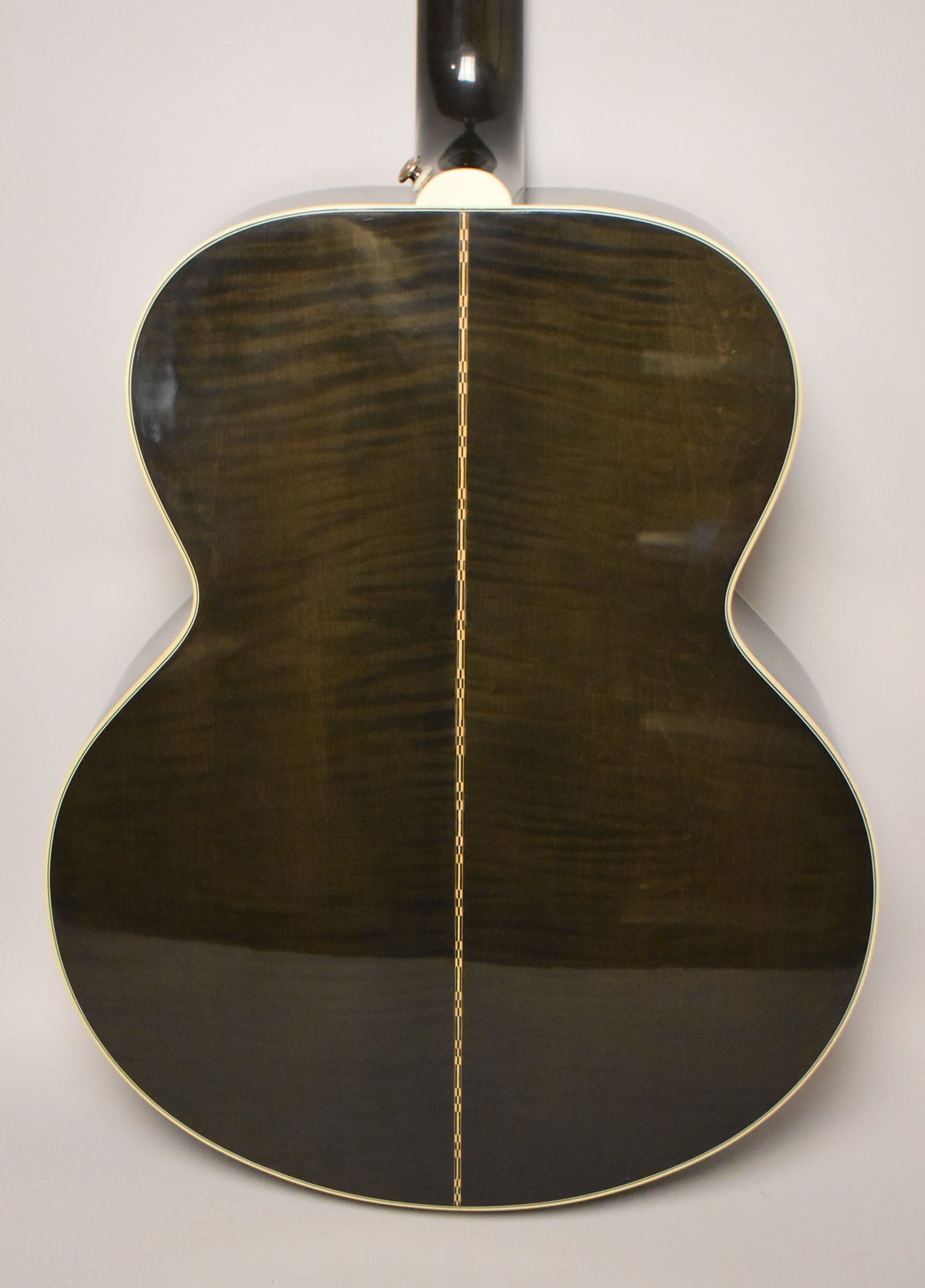 The guitar's back, a glossy trans black with visible wood grain, features a thin, checkered backstrip down the center.