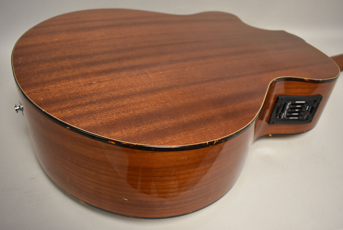 The acoustic bass's natural finish mahogany back and sides show light wear, with a black preamp control panel visible on the upper bout.