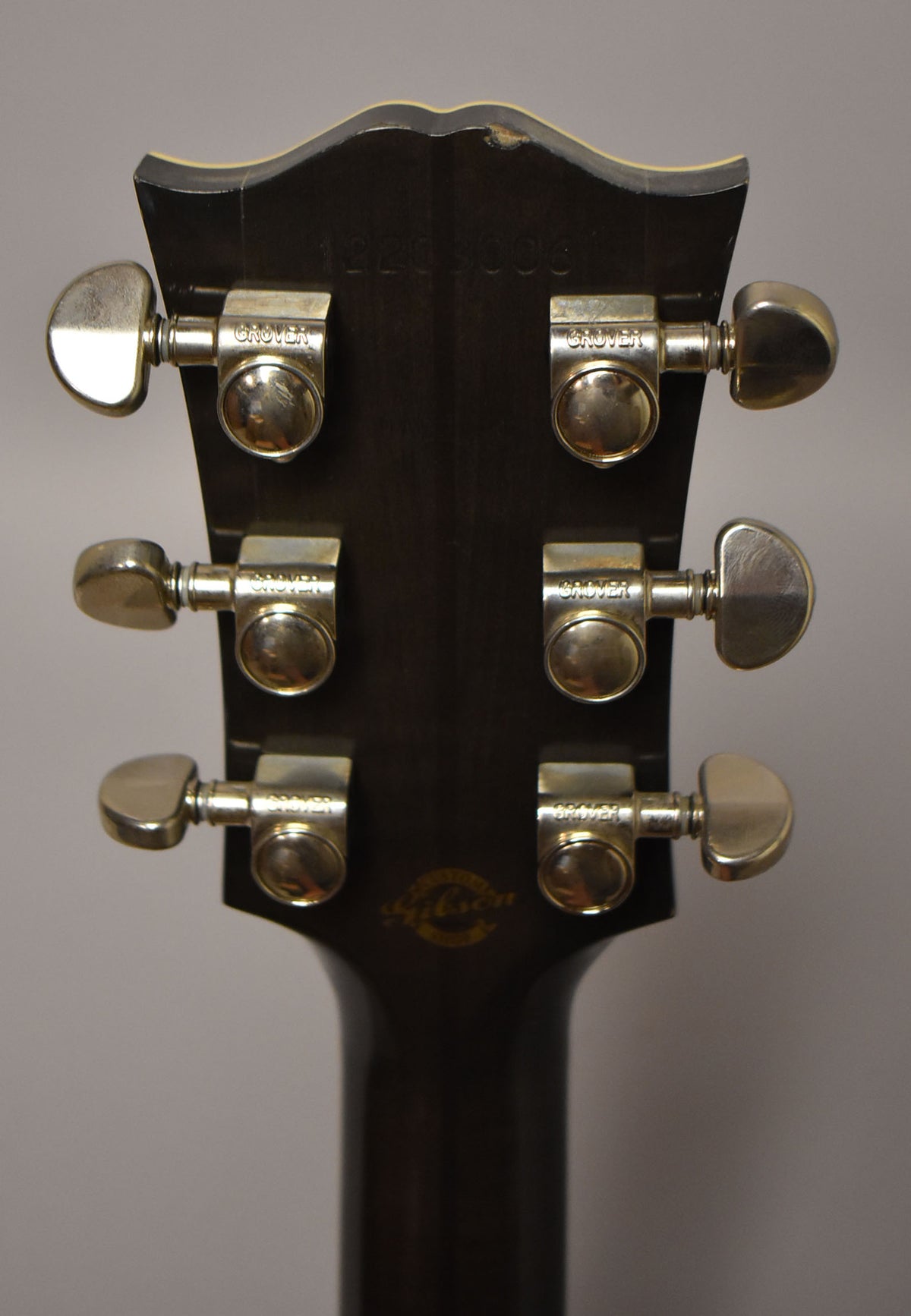 Rear view of the dark brown headstock and neck, showing six chrome Grover tuners and some finish wear on the top edge.