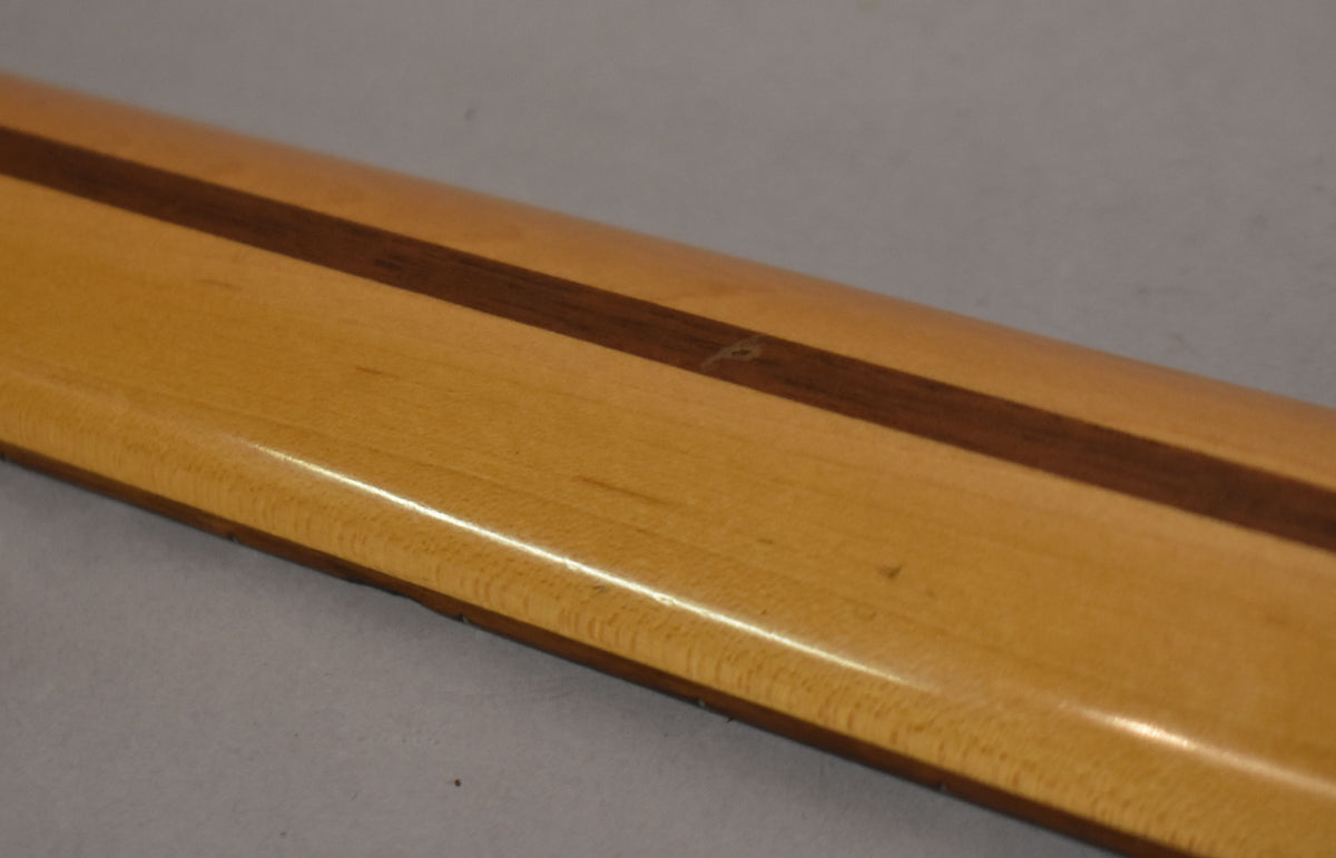 Close-up of the neck's back, showing a light-colored wood with a dark central stripe and a small ding near the stripe.