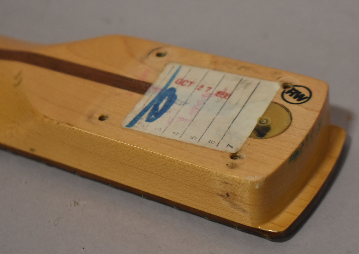 The natural finish maple neck heel, with a dark wood skunk stripe, shows a worn paper label and a circular RW stamp.