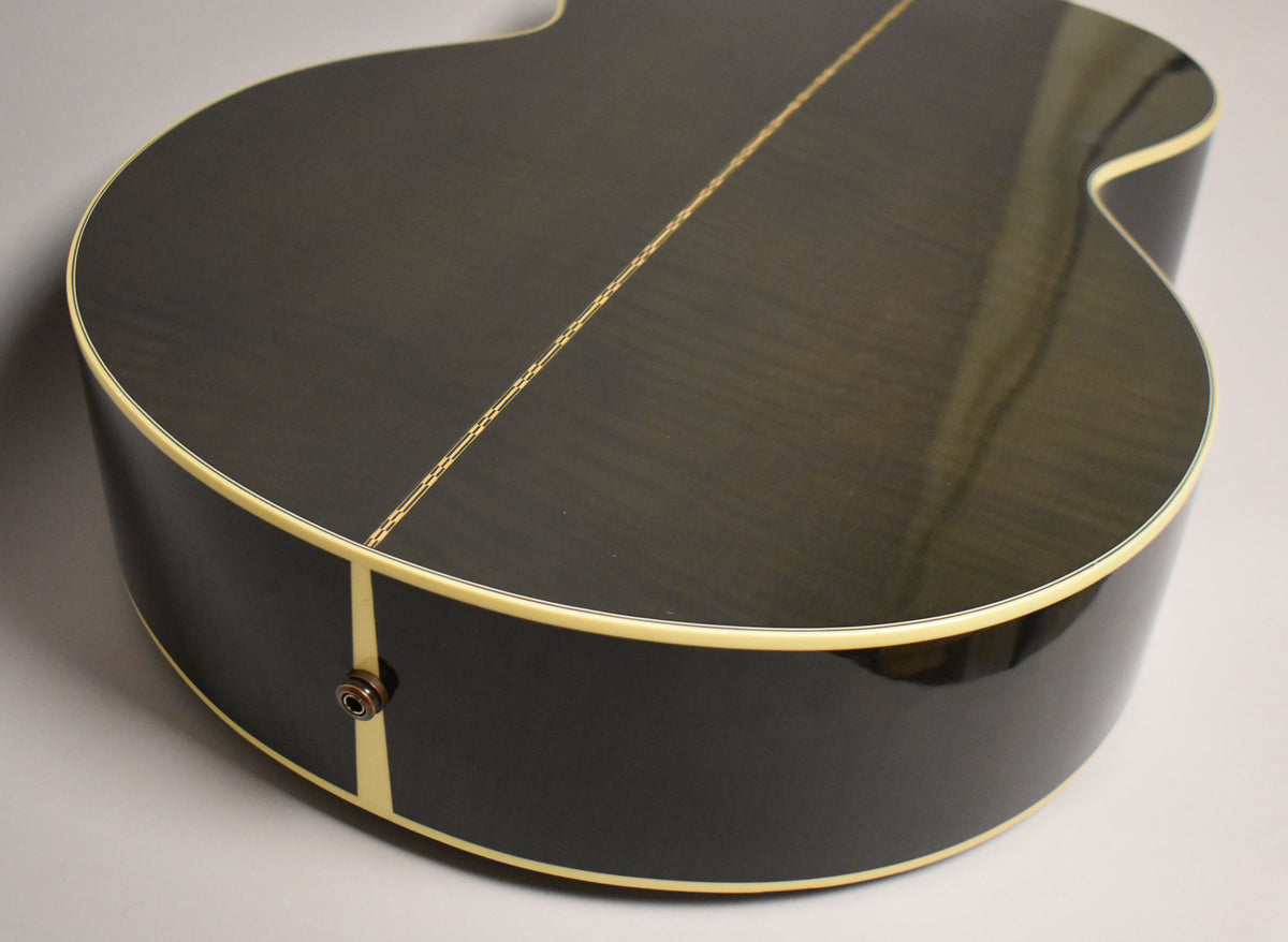 The lower bout of a black acoustic guitar, showing the dark wood grain, cream binding, and an endpin jack.