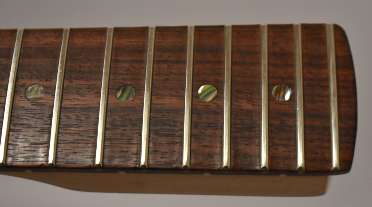 Close-up of the dark rosewood fretboard with four pearloid dot inlays and shiny frets, showing light wear.