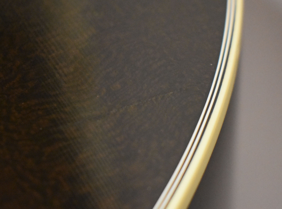 Close-up of the guitar's dark trans black body with visible wood grain, showing a few light scratches and multi-ply cream binding.