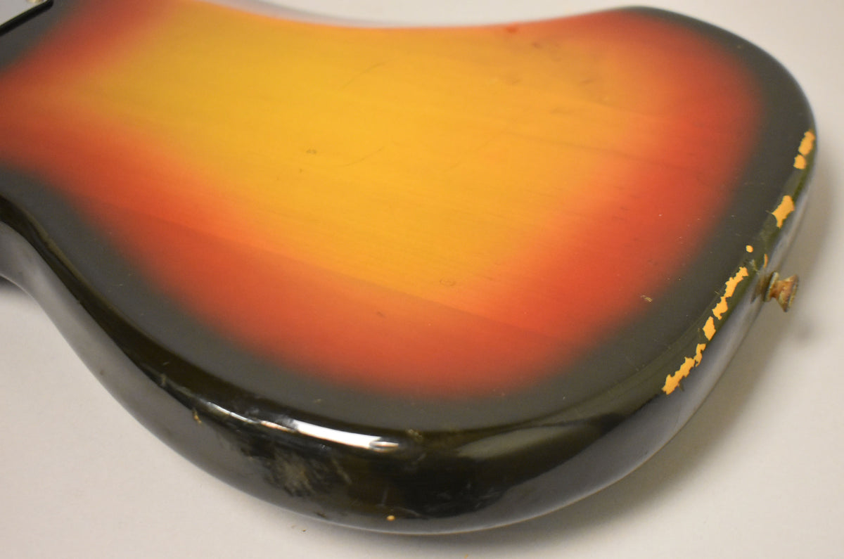The bass body's sunburst finish shows extensive paint chipping along the bottom edge, revealing yellowed wood beneath.