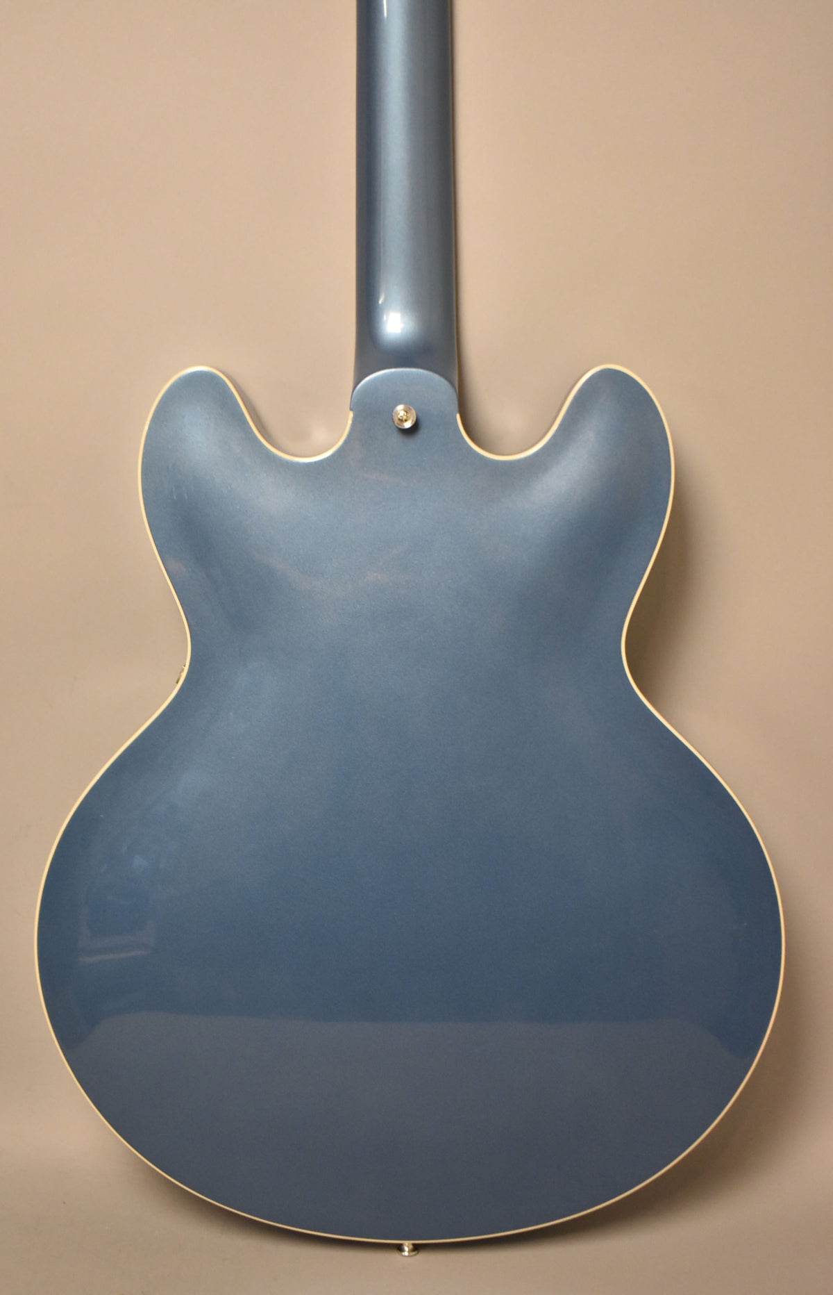 The back of a Pelham Blue guitar with a glossy finish, showing the neck joint and a strap button at the bottom.