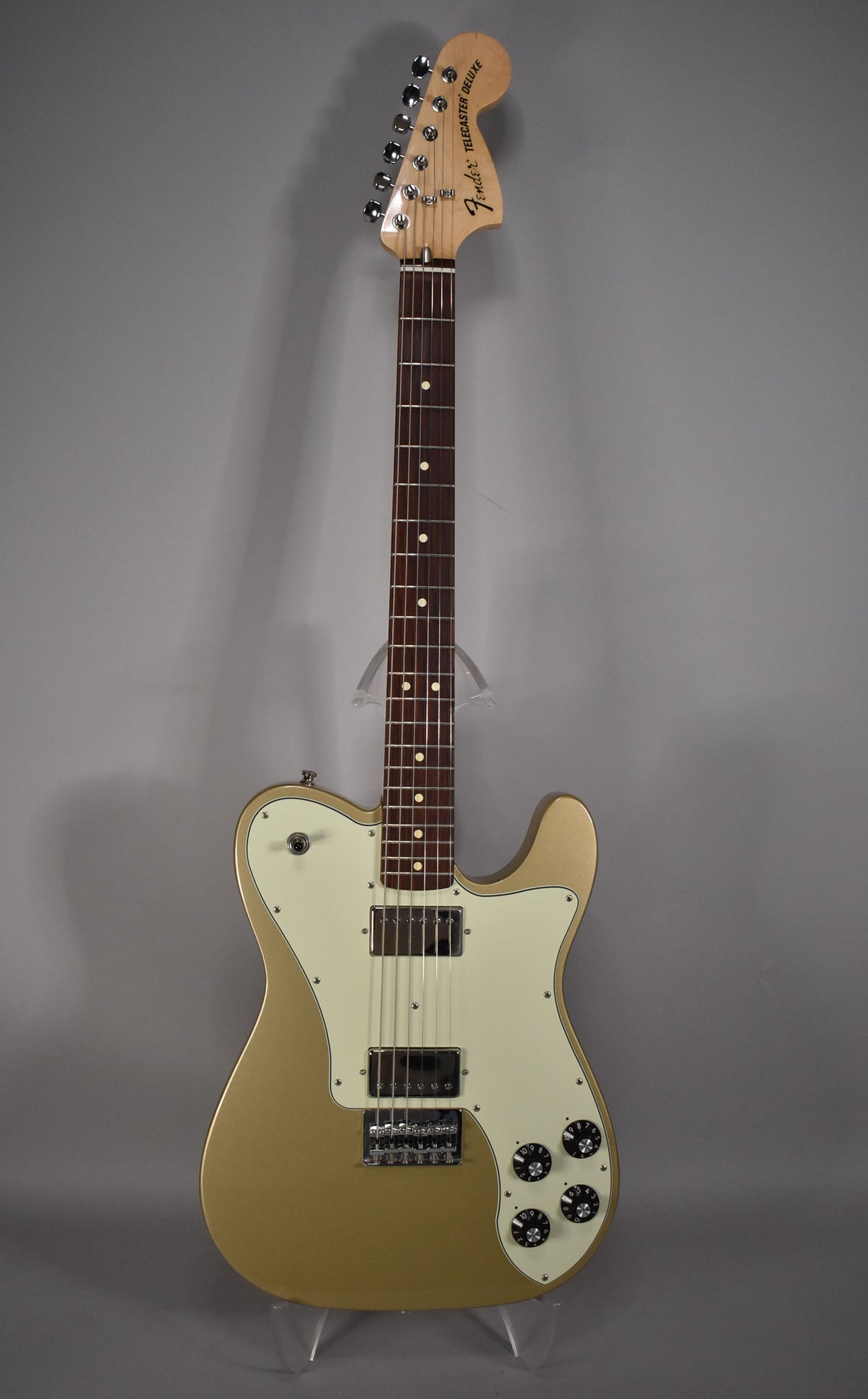 Full front view of a gold electric guitar with an off-white pickguard, two humbucker pickups, and four black control knobs.