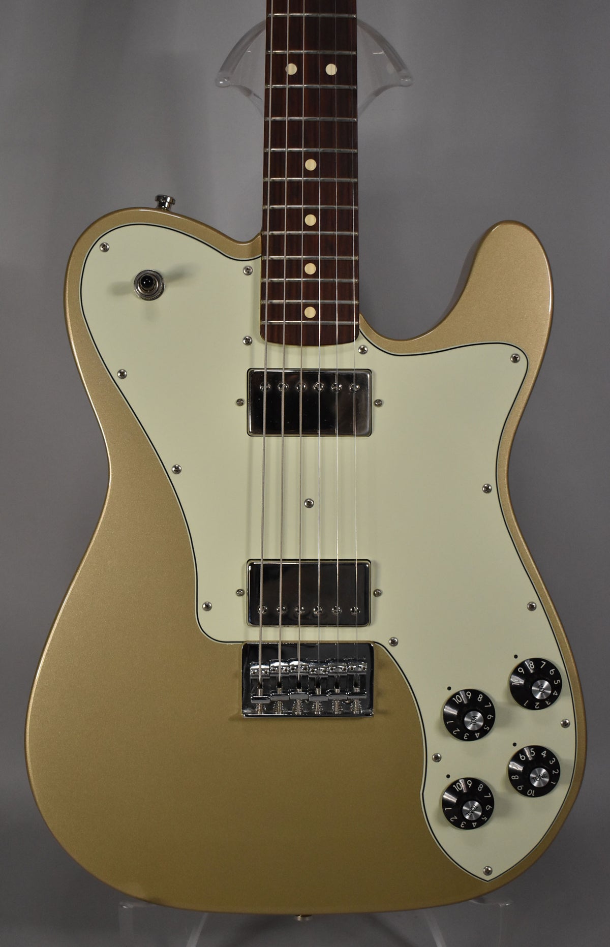 A Shoreline Gold Telecaster Deluxe, framed from the upper neck to the lower body, with a cream pickguard, two humbuckers, and four black control knobs.