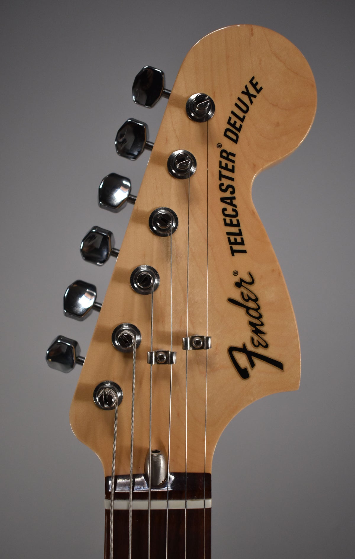 Close-up of the light maple headstock with six chrome tuners, two string trees, and a dark rosewood fretboard.
