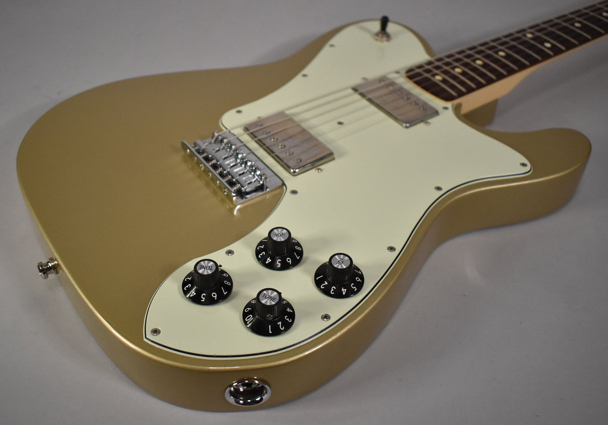 The Shoreline Gold guitar body, with a cream pickguard and four black control knobs, is angled from the lower right.
