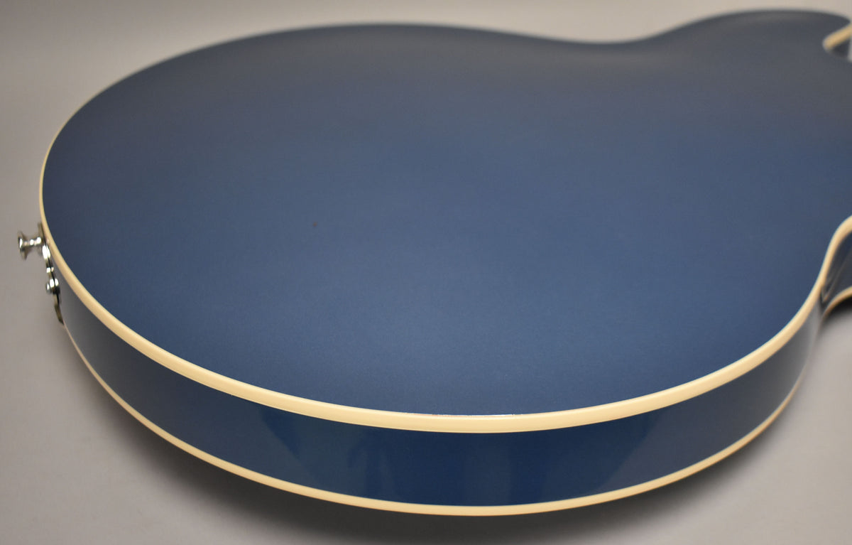 The back of a Pelham Blue semi-hollow guitar, angled from the lower bout, shows cream binding and a single strap button.