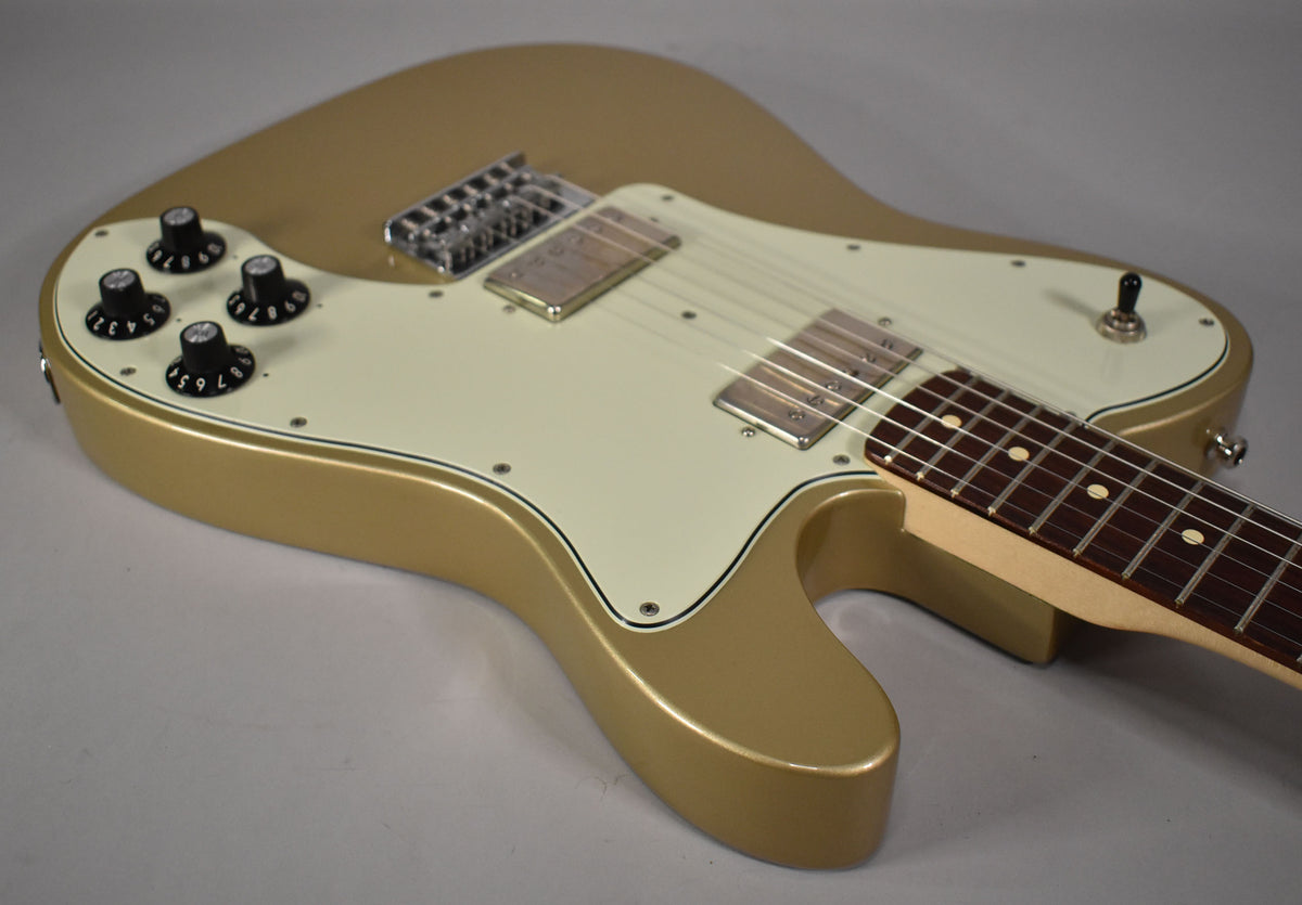The Shoreline Gold guitar body is angled from the upper left, showing the white pickguard, four black control knobs, and two humbuckers.