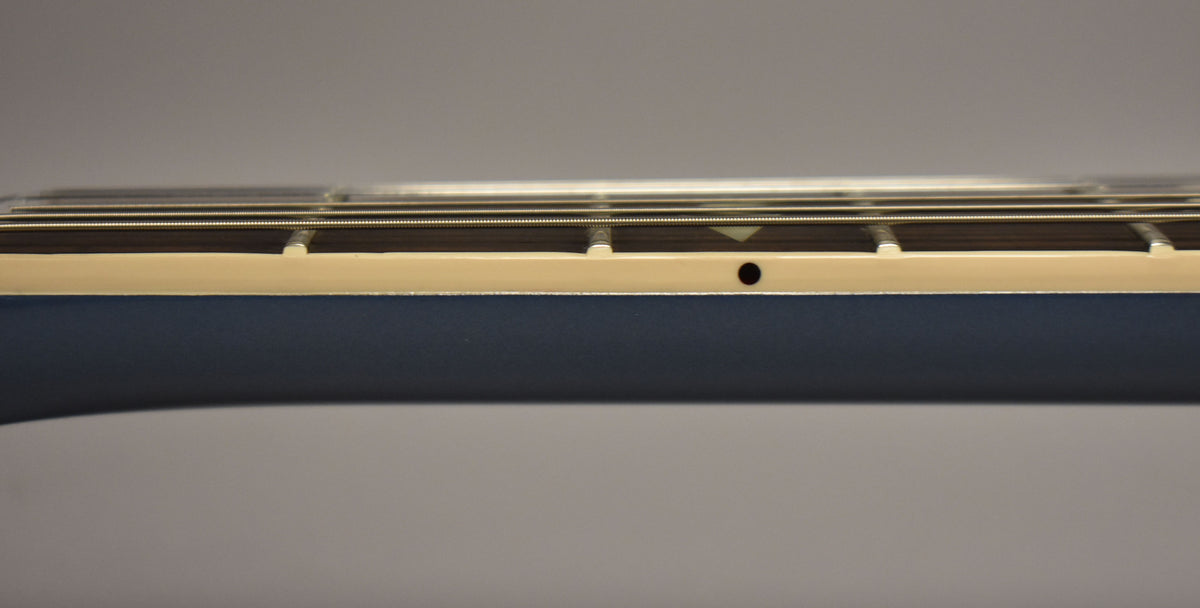 The Pelham Blue guitar neck, with cream binding, is shown in profile, revealing a side dot marker and fret wire.