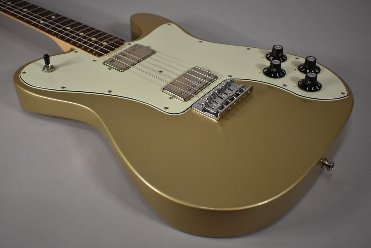 Shoreline Gold guitar body with an off-white pickguard, two humbuckers, a chrome hardtail bridge, and four black control knobs.