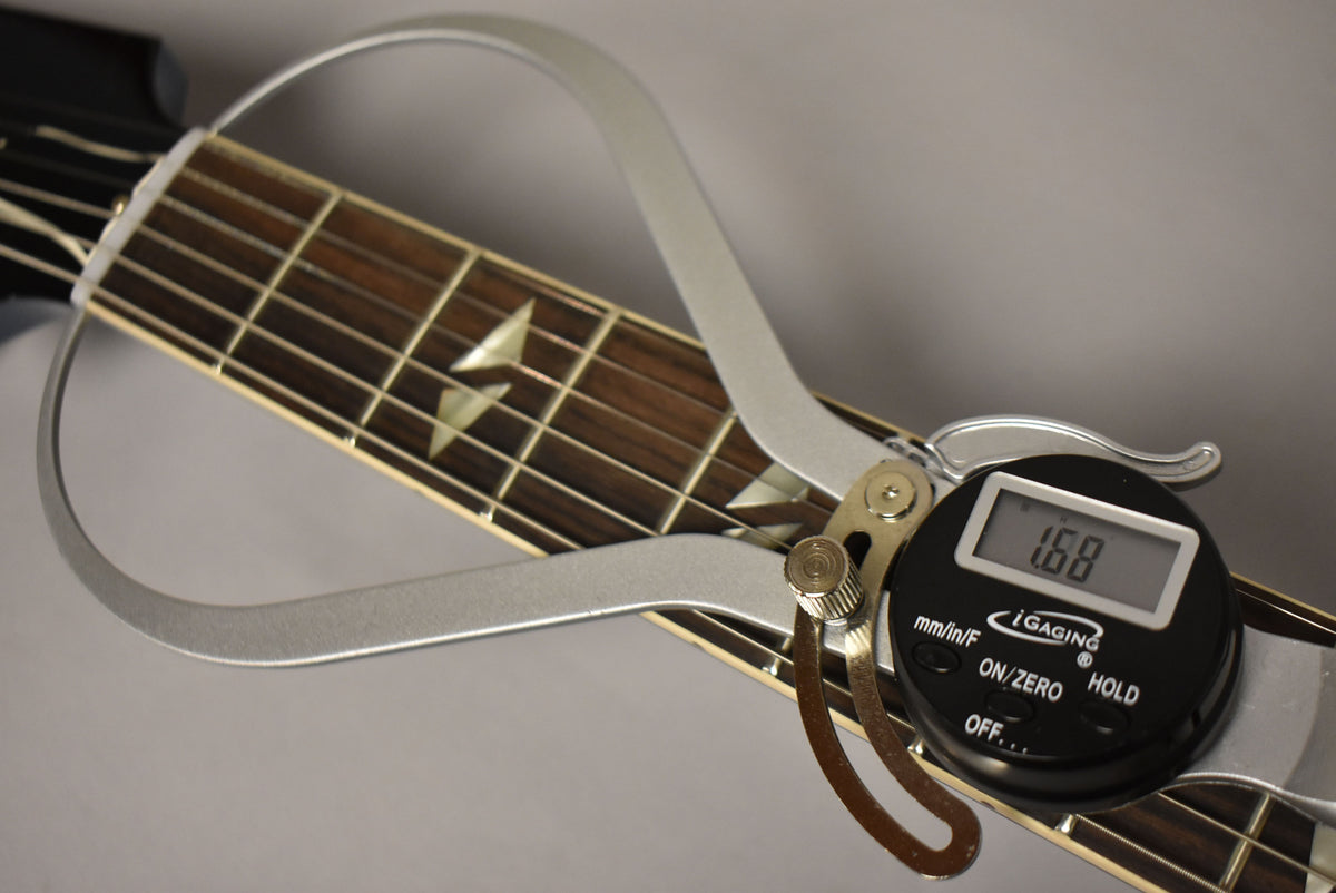 A digital caliper measures the nut width of the dark rosewood fretboard with split parallelogram inlays, displaying "1.68".