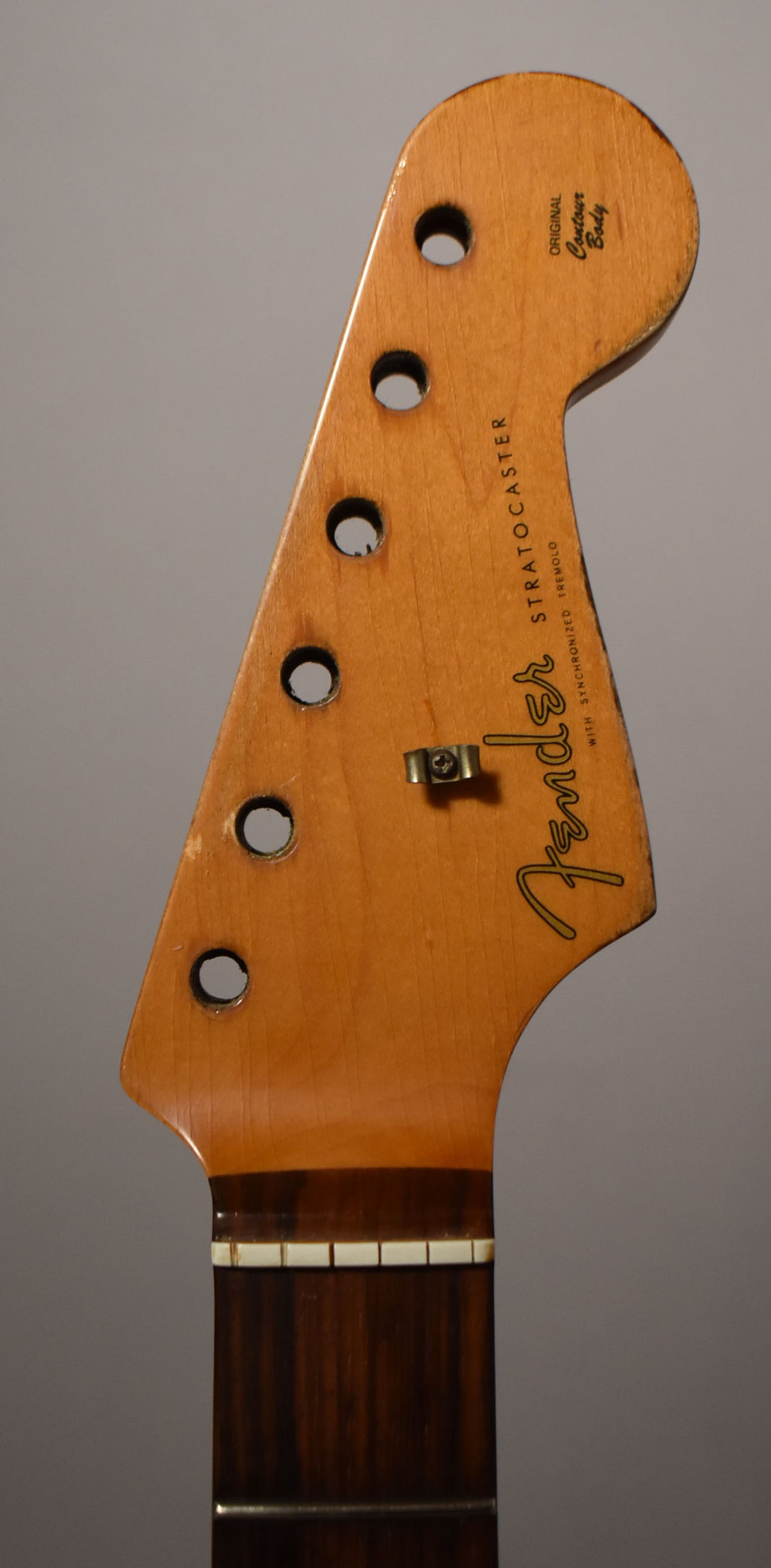 The light brown headstock, with a dark rosewood fretboard, shows six tuner holes, a string tree, and relic wear.