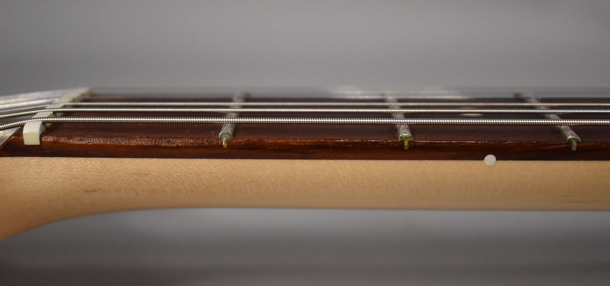 Close-up of the guitar's neck, showing the maple neck, dark rosewood fretboard, frets, strings, and a white side dot marker.