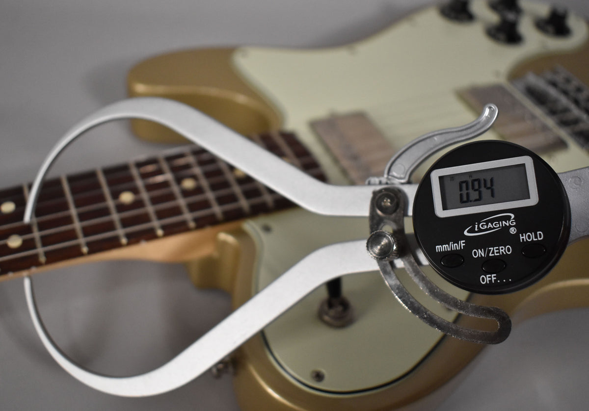 A digital caliper measures the Shoreline Gold guitar's fret height at 0.94, with the rosewood fretboard and body visible.