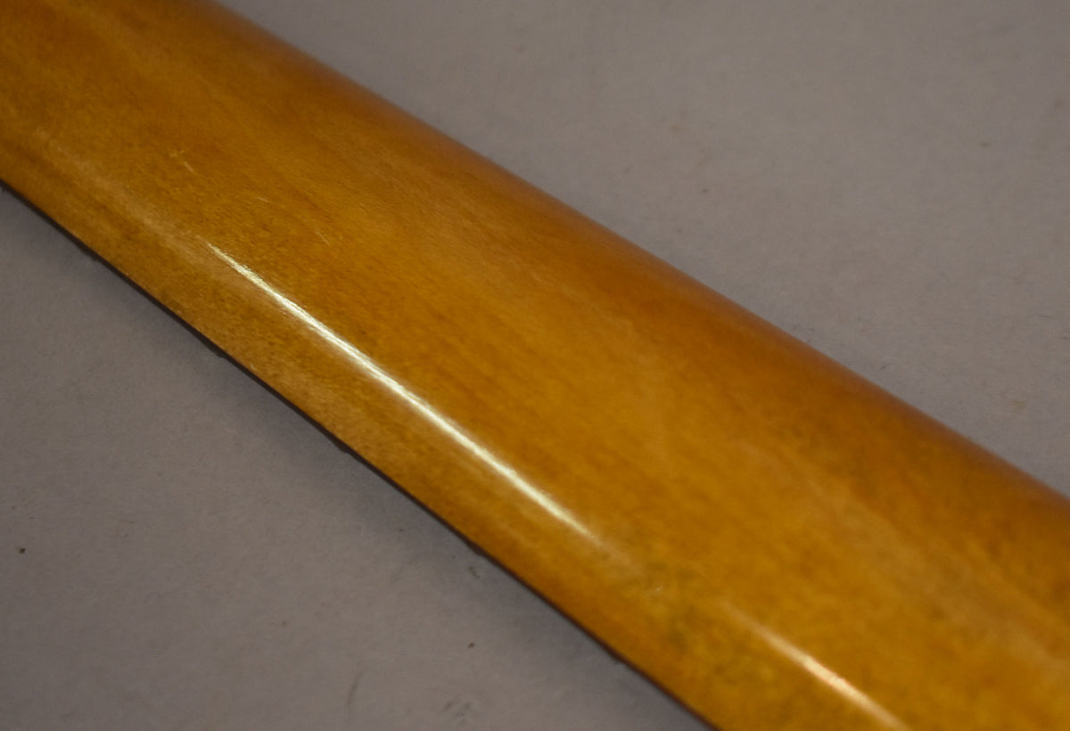 The back of a glossy amber guitar neck is shown diagonally, with visible wear and light scratches along its length.