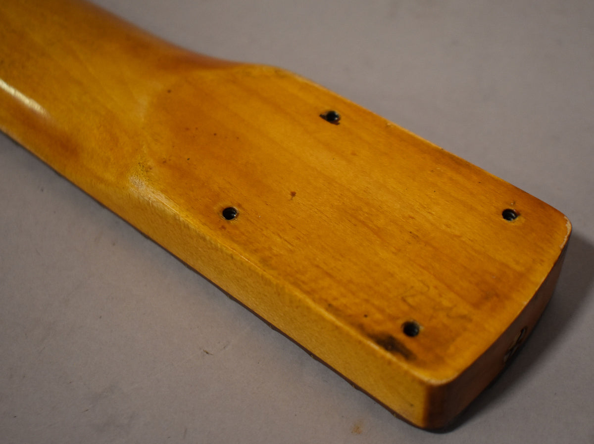 The heel of a relic'd amber-finished Stratocaster neck, showing four black screw holes and dark wear marks on the wood.