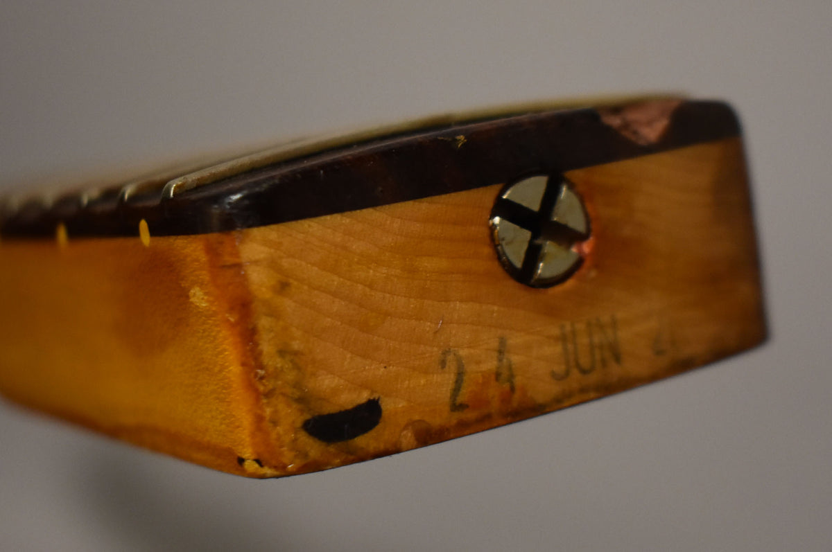 The heel of a relic'd maple Stratocaster neck, showing a dark brown fretboard, a gold screw, and "24 JUN" stamped into the wood.