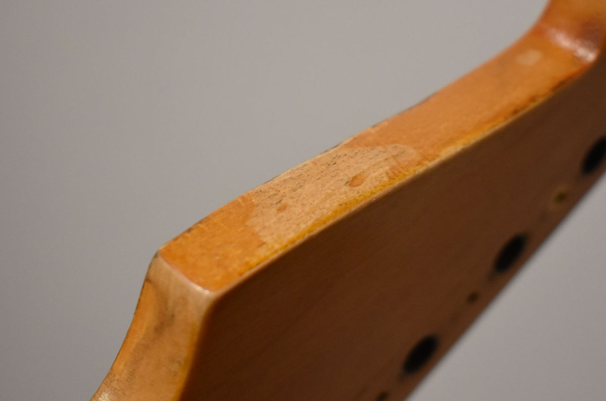 Close-up of the neck's side, showing worn-through finish on the light brown wood, with dark tuner holes visible on the right.
