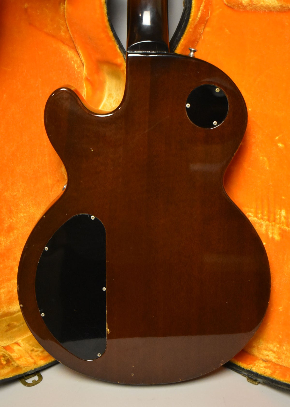 The back of a glossy dark brown guitar with two black control plates, showing some minor finish wear and dings.