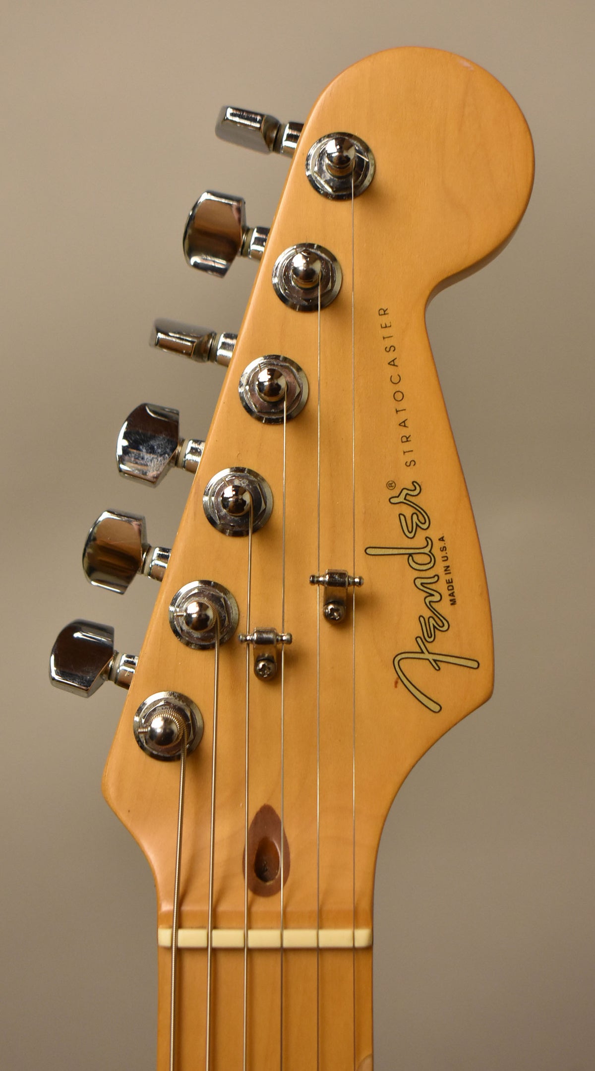 Close-up of the guitar's headstock, showing six chrome tuners, two string trees, and a dark wood plug covering the truss rod access.