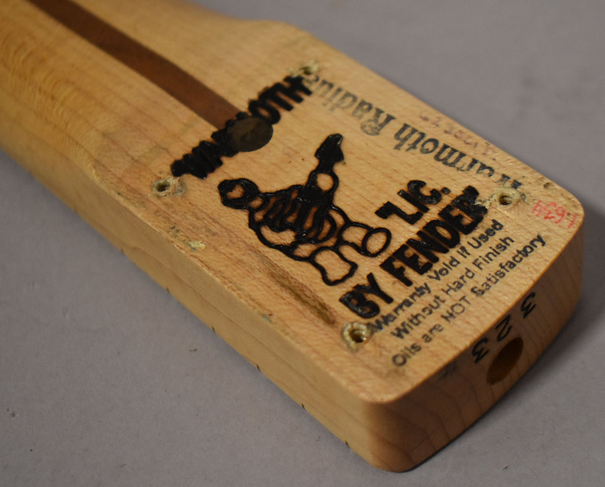 The heel of a light maple neck, with dark wood stripe, shows black stamped text and four screw holes with minor wear.