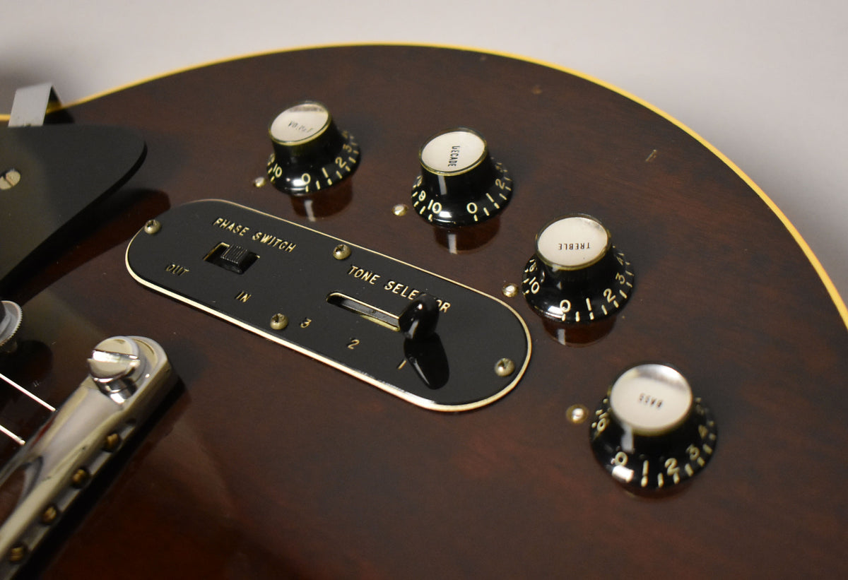 Close-up of the dark walnut body, showing the black control plate with "Phase Switch" and "Tone Selector," plus four black knobs.