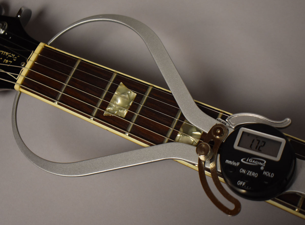 A close-up of the guitar's dark rosewood fretboard with trapezoid inlays, measured by a digital caliper displaying "1.72".
