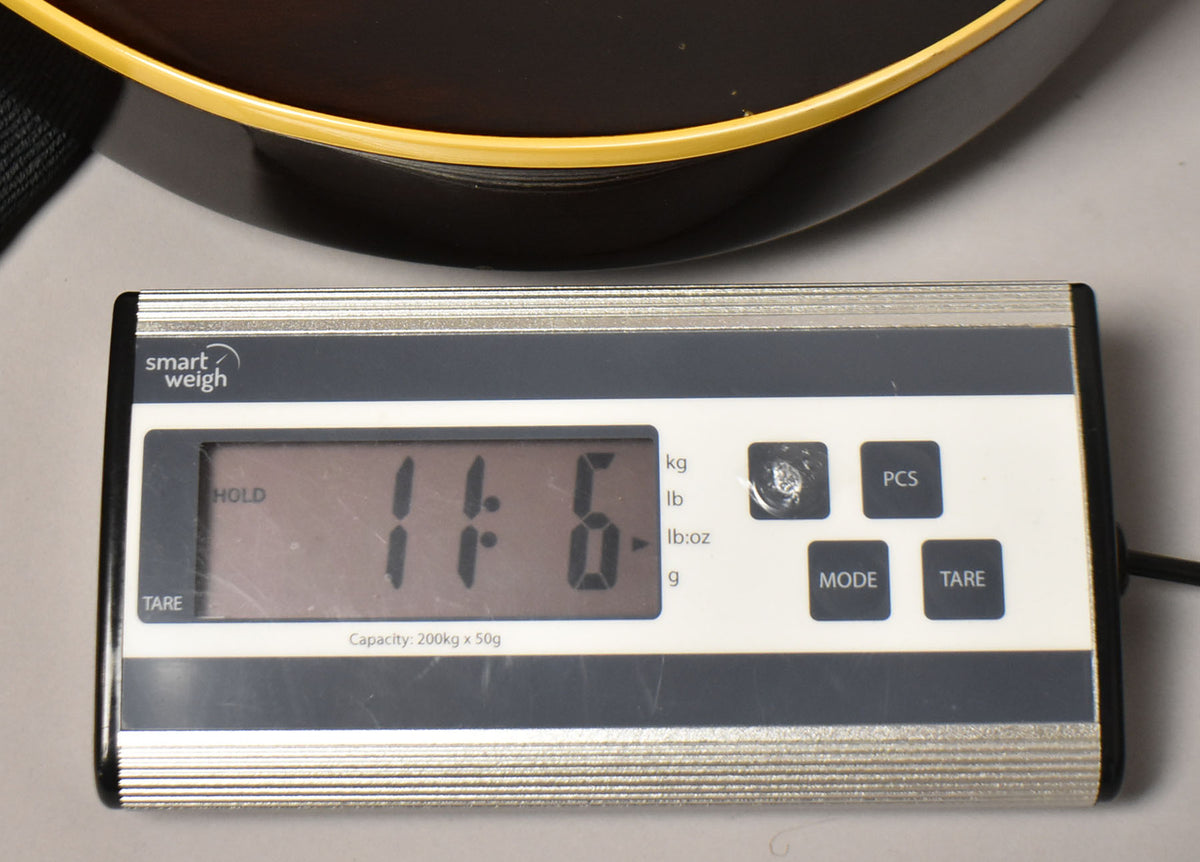 A digital scale displays "11.6" lbs, with the dark walnut body and cream binding of the guitar visible above.